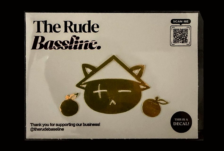 A gold cat decal on a Rude Bassline backing card in a clear sleeve