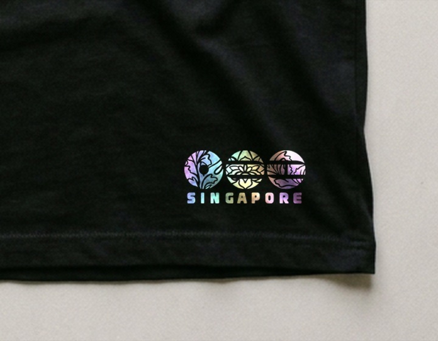 Close-up of the holographic Singapore transfer at the hem of a black t-shirt