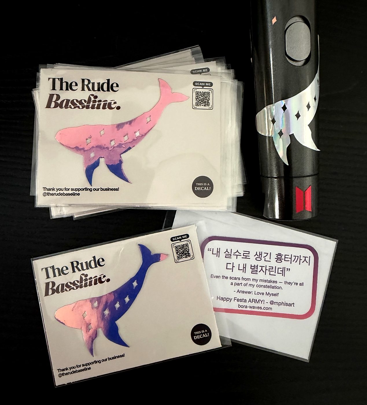 Holographic whale decals on The Rude Bassline backing cards in pink and blue, with one whale applied to the handle of an ARMY Bomb